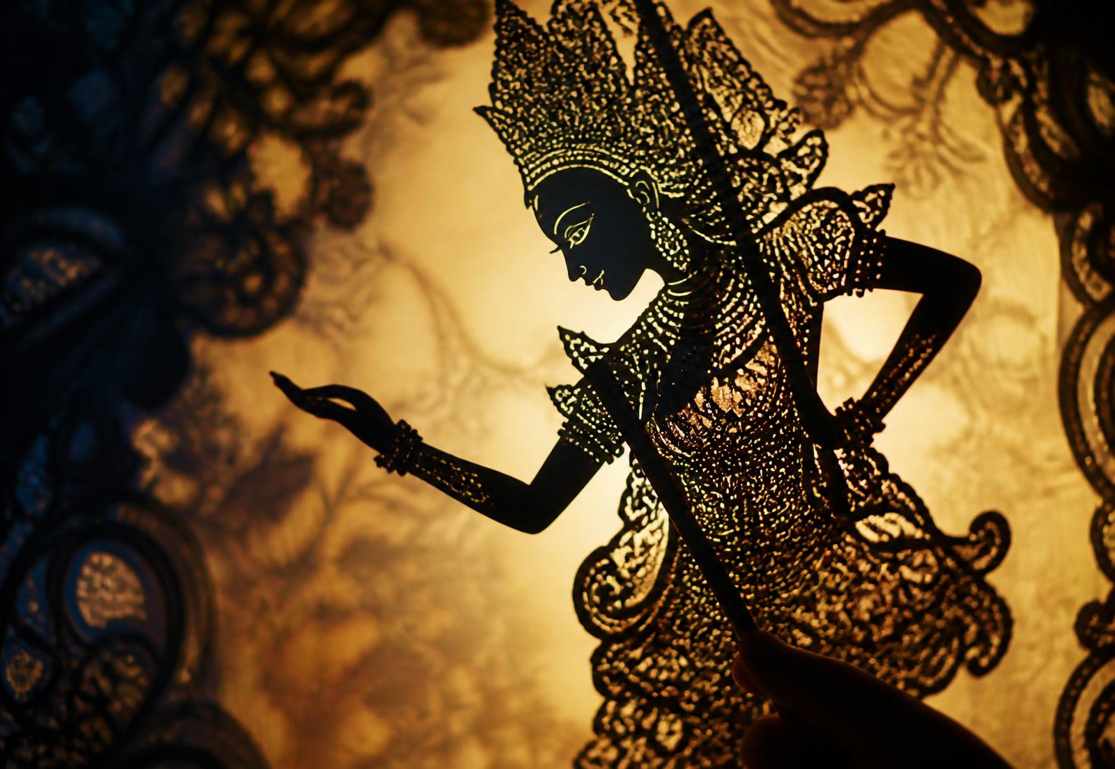 Ornate cut-paper puppet held against a glowing screen